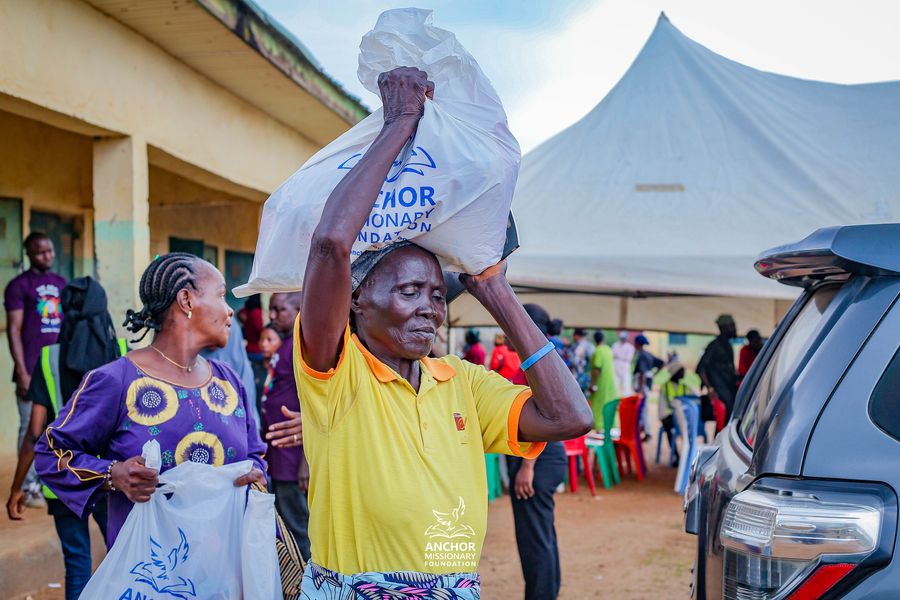 A woman carries an Anchor Missionary Foundation relief bag on her head at a community distribution